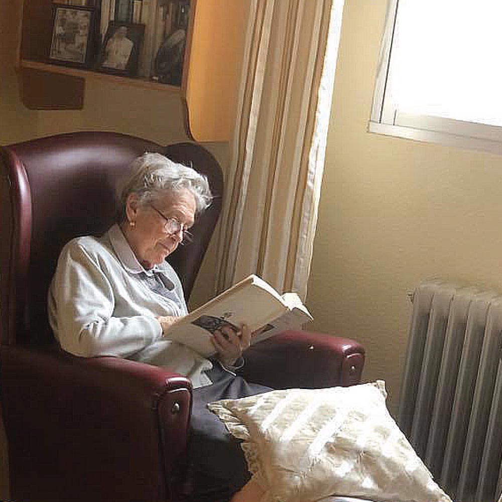 Residente leyendo en habitación geriátrica residencia El Casar